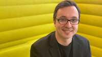 Porträtfoto von Alexey Chernikov vor gelbem Hintergrund, freundlich und frontal fotografiert.